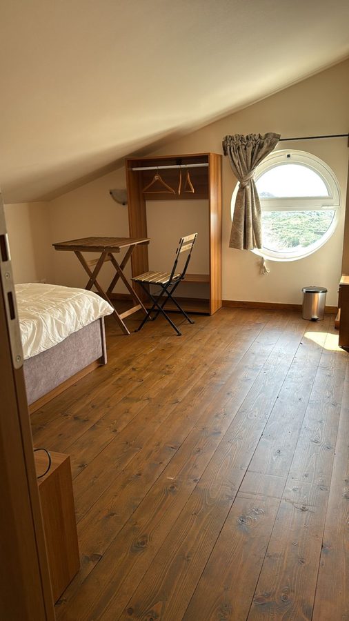 Attic bedroom with round porthole window and wooden floors