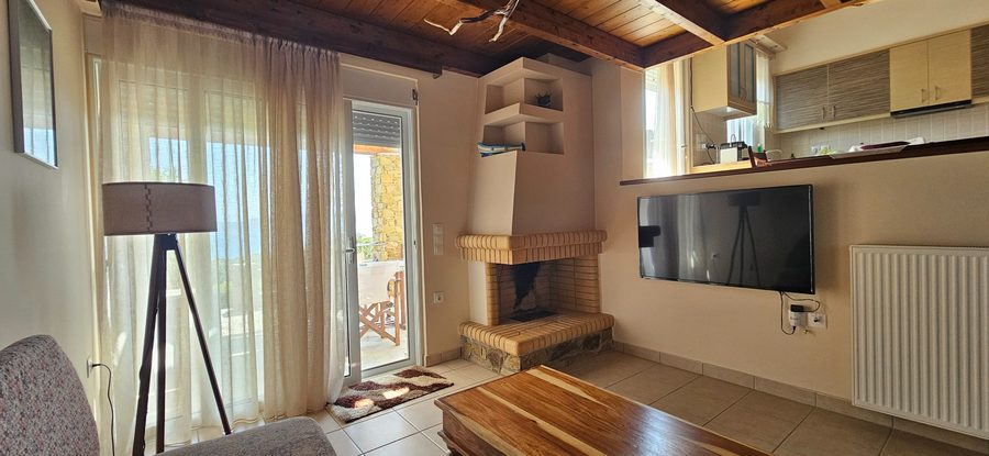 Living room with fireplace, wooden beams, and TV